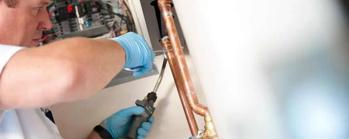 Water heater repair technician testing copper pipe connections and controls in Lakeland, FL